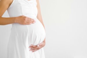 A pregnant woman in a white dress holds her belly. A recent article about Texas' abortion ban refers to "birthing people" instead of "women." © By fotoduets/stock.adobe.com