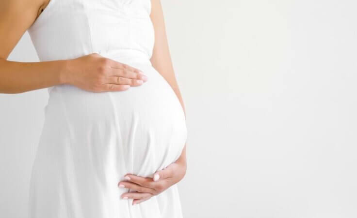 A pregnant woman in a white dress holds her belly. A recent article about Texas' abortion ban refers to "birthing people" instead of "women." © By fotoduets/stock.adobe.com
