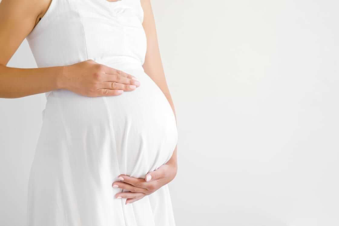 A pregnant woman in a white dress holds her belly. A recent article about Texas' abortion ban refers to "birthing people" instead of "women." © By fotoduets/stock.adobe.com