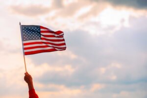 A lone hand waves an American flag in front of a clouds at sunset. © By nicoletaionescu/stock.adobe.com. What role does morality play in a democracy?