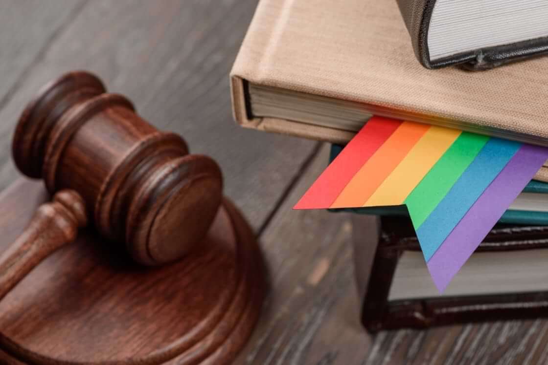 A wooden gavel sits to the left of a stack of books, one of which has a rainbow-colored bookmark within it. © By yuriygolub /stock.adobe.com. Parents from Christian, Muslim, and Jewish backgrounds in Montgomery County, Maryland, have brought a lawsuit against the district seeking to shield their children from sexual LGBTQ materials.
