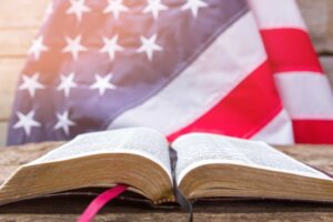 Una Biblia abierta frente a una bandera estadounidense. By DenisProduction.com/stock.adobe.com