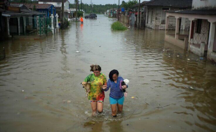 Residents wade through a street flooded by rains brought on by Hurricane Idalia, in Batabano, Cuba, Tuesday, Aug. 29, 2023. Idalia strengthened into a hurricane Tuesday and barreled toward Florida's Gulf Coast. (AP Photo/Ramon Espinosa)