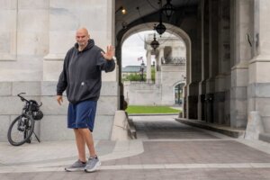 FILE - Sen. John Fetterman, D-Pa., waves to members of the media, Monday, April 17, 2023, on Capitol Hill in Washington. (AP Photo/Jacquelyn Martin, File). Amid controversy, Chuck Schumer announced a relaxation of the Senate dress code to accommodate Sen. John Fetterman's refusal to wear a suit.