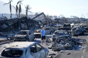 A man walks through wildfire wreckage Friday, Aug. 11, 2023, in Lahaina, Hawaii. Hawaii emergency management records show no indication that warning sirens sounded before people ran for their lives from wildfires on Maui that wiped out a historic town. (AP Photo/Rick Bowmer)