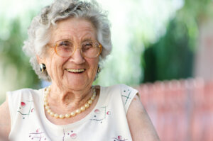 An elderly woman beams with a smile. By Hunor Kristo/stock.adobe.com