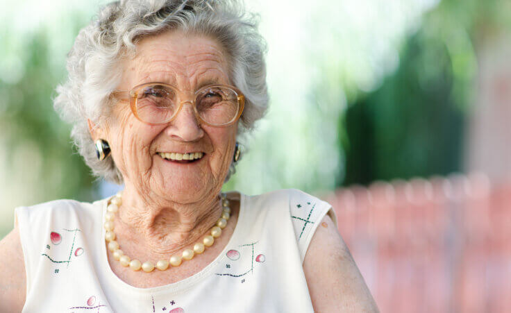 An elderly woman beams with a smile. By Hunor Kristo/stock.adobe.com