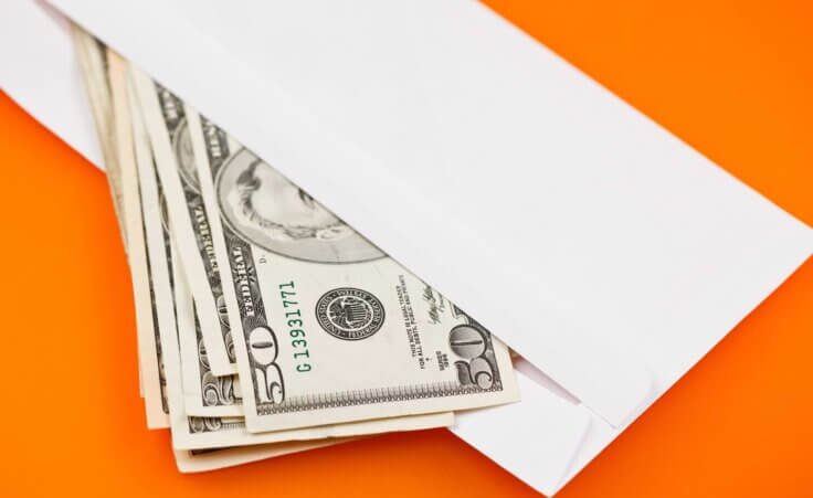 Money spills out of an open white envelope against an orange background. By Jiri Hera/stock.adobe.com