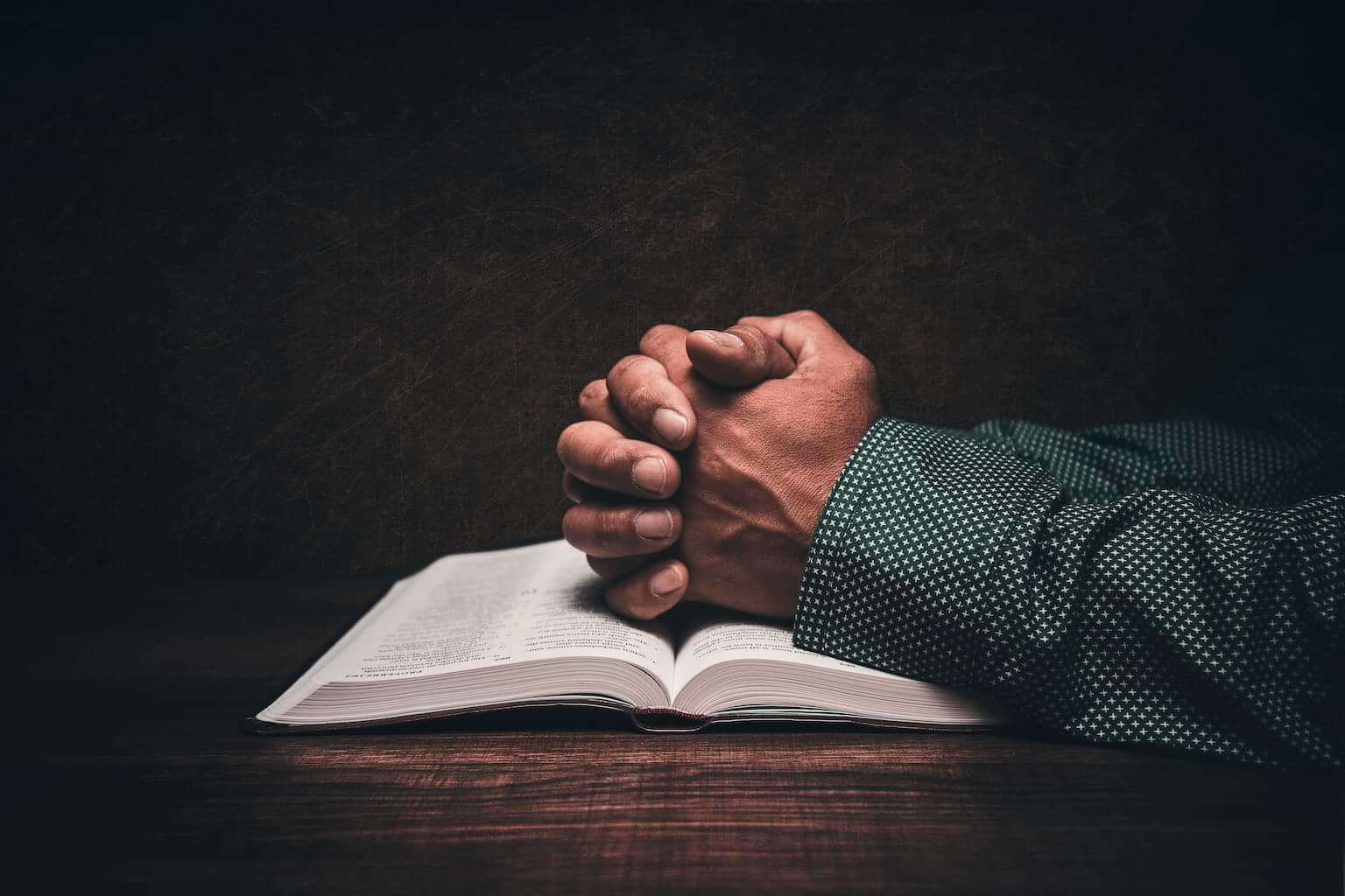 Hands folded in prayer on top of a Bible. By JavierArtPhotography/stock.adobe.com