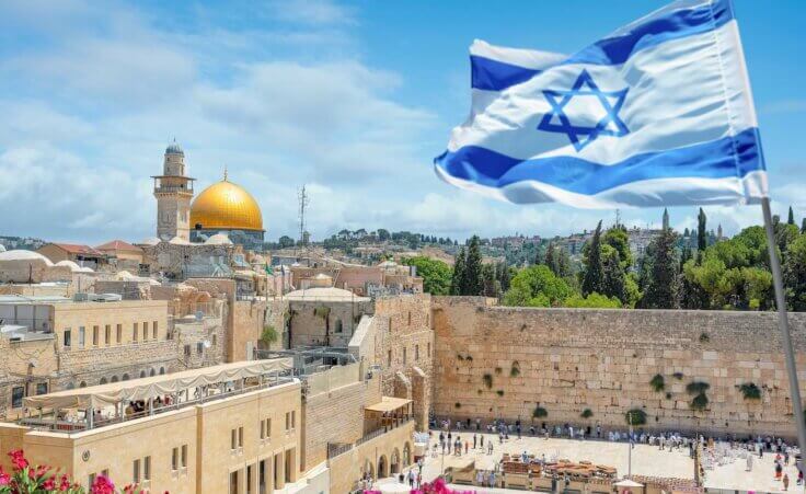 The Israel flag flies above the Western Wall in Jerusalem with the Dome of the Rock in the background. By Nick Brundle /stock.adobe.com