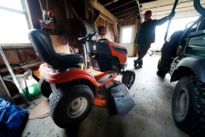 Trailer park owner Ed Smith looks at one of Geoffrey Holt's riding mowers at Stearns Park, Wednesday, Nov. 15, 2023, in Hinsdale, N.H. (AP Photo/Robert F. Bukaty)
