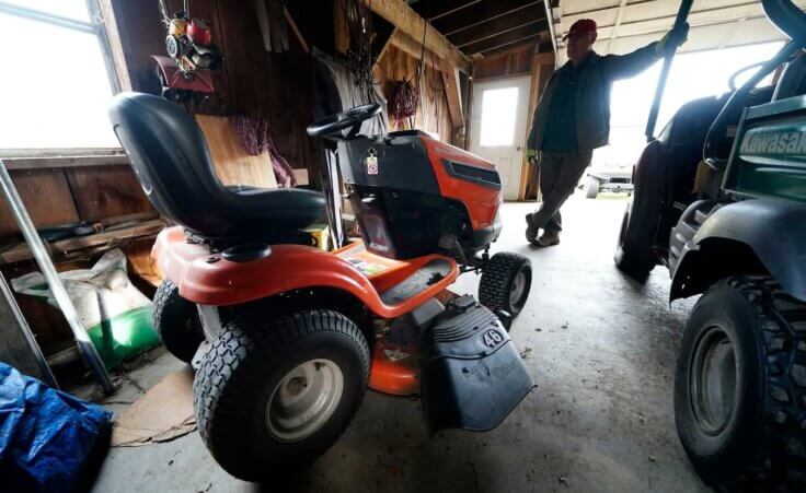 Trailer park owner Ed Smith looks at one of Geoffrey Holt's riding mowers at Stearns Park, Wednesday, Nov. 15, 2023, in Hinsdale, N.H. (AP Photo/Robert F. Bukaty)