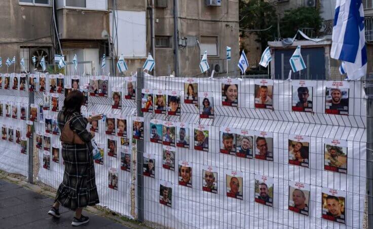 A woman looks at photographs of hostages, mostly Israeli civilians who were abducted during the Oct. 7, unprecedented Hamas attack on Israel, in Ramat Gan, Israel, Wednesday, Nov. 22, 2023. (AP Photo/Oded Balilty)