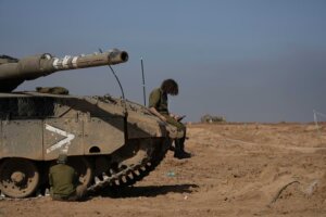 Israeli soldiers work on a tank in a staging area in southern Israel, near the border with Gaza Strip, on Friday, Nov. 24, 2023. the first day of what is meant to be a four-day cease-fire in the Israel-Hamas war. (AP Photo/Tsafrir Abayov)