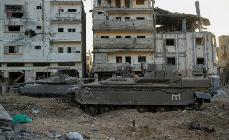 An Israeli armored personnel carrier and a tank are seen next to destroyed buildings during a ground operation in the Gaza Strip on Wednesday, Nov. 8, 2023. (AP Photo/Ohad Zwigenberg) Is Israel committing genocide?