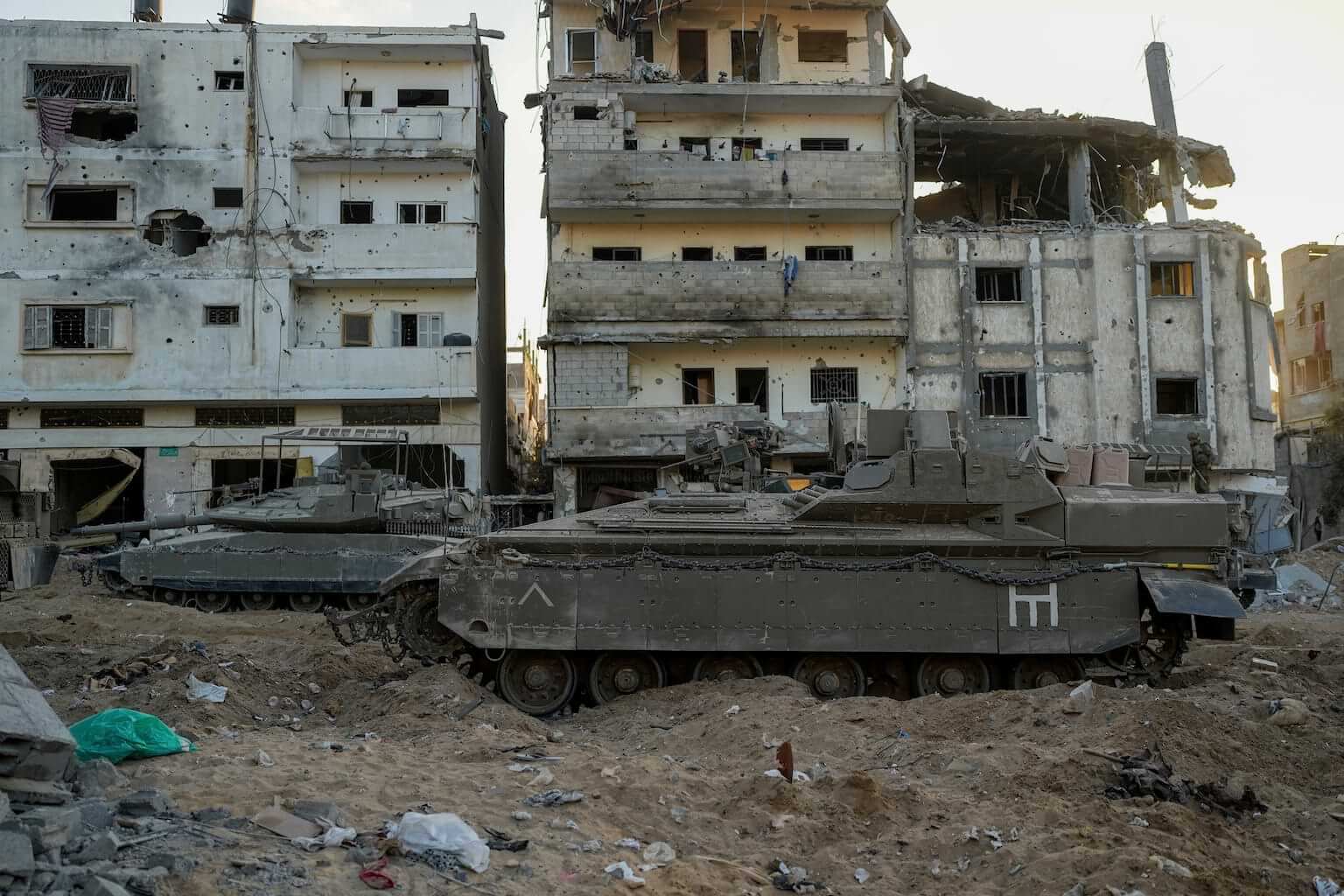 An Israeli armored personnel carrier and a tank are seen next to destroyed buildings during a ground operation in the Gaza Strip on Wednesday, Nov. 8, 2023. (AP Photo/Ohad Zwigenberg) Is Israel committing genocide?
