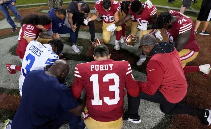 San Francisco 49ers quarterback Brock Purdy (13) kneels in prayer with teammates and Dallas Cowboys wide receiver Brandin Cooks (3) after an NFL football game in Santa Clara, Calif., Sunday, Oct. 8, 2023. (AP Photo/Godofredo A. Vásquez)