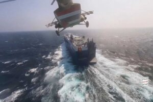 This photo released by the Houthi Media Center shows a Houthi forces helicopter approaching the cargo ship Galaxy Leader on Sunday, Nov. 19, 2023. Yemen's Houthis have seized the ship in the Red Sea off the coast of Yemen after threatening to seize all vessels owned by Israeli companies. (Houthi Media Center via AP)