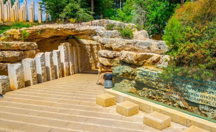 The entrance to the Yad Vashem Children's Memorial in Jerusalem shows pillars in the background and a walkway into an underground memorial. Israelis prefer the term "Shoah" over Holocaust. dudlajzov/stock.adobe.com