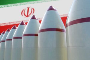 A 3D rendering of eight white-and-red missiles in front of an Iranian flag, illustrating Iran's growing nuclear capabilities. By vchalup/stock.adobe.com