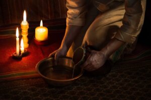 A stylized image of Jesus bending down and pouring water from a jar into a bowl in preparation to wash feet. The "He Gets Us" campaign, funded by Hobby Lobby's Green family, that aired during Super Bowl LVIII showed Christians washing others' feet. By Marina/stock.adobe.com