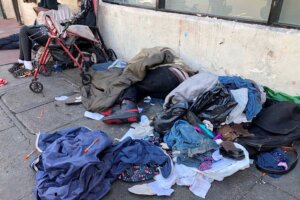 FILE - Sleeping people, discarded clothes and used needles are seen on a street in the Tenderloin neighborhood in San Francisco, July 25, 2019. (AP Photo/Janie Har, File)