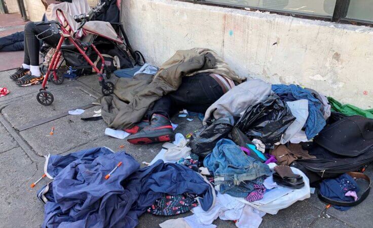 FILE - Sleeping people, discarded clothes and used needles are seen on a street in the Tenderloin neighborhood in San Francisco, July 25, 2019. (AP Photo/Janie Har, File)