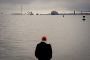 A person at Fort McHenry views a container ship as it rests against wreckage of the Francis Scott Key Bridge on Wednesday, March 27, 2024, in Baltimore, Md. (AP Photo/Matt Rourke)
