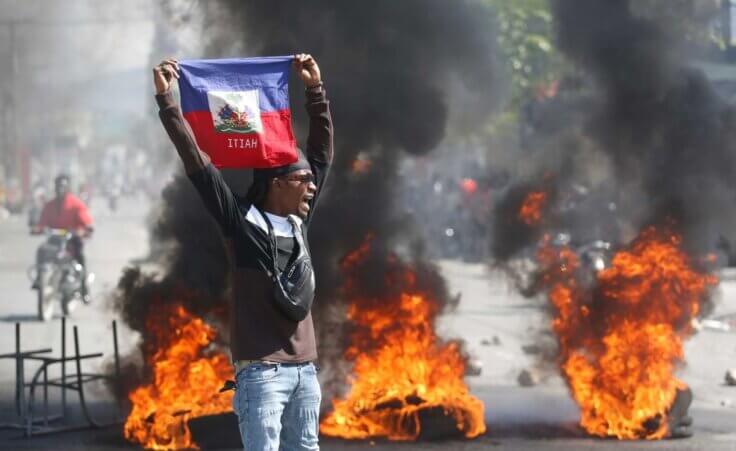 A demonstrator holds up an Haitian flag during protests demanding the resignation of Prime Minister Ariel Henry in Port-au-Prince, Haiti, Friday, March 1, 2024. (AP Photo/Odelyn Joseph)