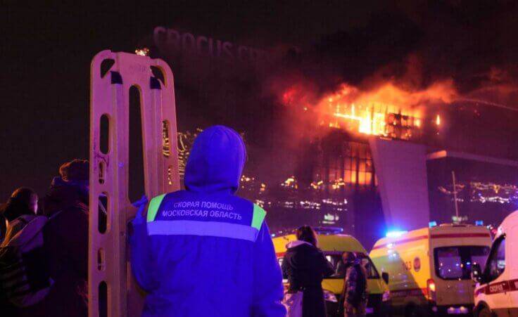 A medic stands near ambulances parked outside the burning building of the Crocus City Hall on the western edge of Moscow, Russia, Friday, March 22, 2024. (AP Photo/Vitaly Smolnikov)