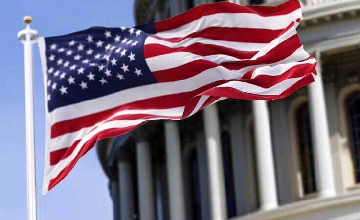 The American flag waves in front of the US Capitol building. By rarrarorro/stock.adobe.com