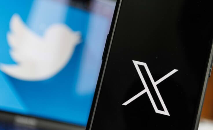 In the background, the Twitter bird logo appears on a computer monitor. In the foreground, the X logo is seen on a black phone screen. By Rokas/stock.adobe.com