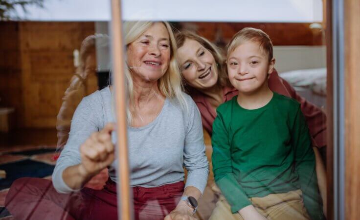 Boy with Down syndrome with his mother and grandmother. By Halfpoint/Stock.Adobe.com