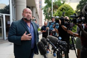 Right-wing conspiracy theorist Alex Jones speaks to the media as he arrives at the federal courthouse for a hearing in front of a bankruptcy judge Friday, June 14, 2024, in Houston. The judge is expected to rule on whether to liquidate Jones' assets to help pay the $1.5 billion he owes for his false claims that the Sandy Hook Elementary School shooting was a hoax. (AP Photo/David J. Phillip)