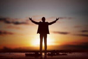 Silhouette of businessman with raised hands, praying to God. By Leo Lintang/stock.adobe.com