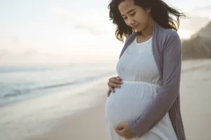 Worried pregnant woman stands on the beach. Image used to illustrate the declining birth rate in America. By Odua Images/stock.adobe.com