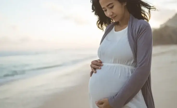 Worried pregnant woman stands on the beach. Image used to illustrate the declining birth rate in America. By Odua Images/stock.adobe.com