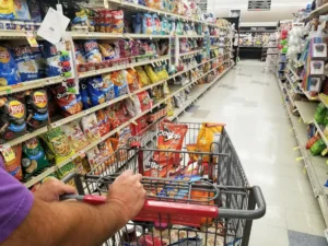 Pushing a cart on the snacks aisle inside a grocery shop. By K.A/stock.adobe.com