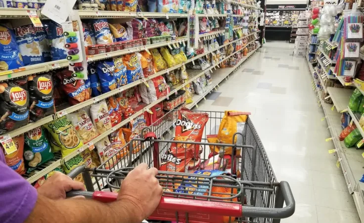 Pushing a cart on the snacks aisle inside a grocery shop. By K.A/stock.adobe.com