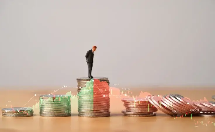 Miniature figure standing on coins stacking with increasing and decreasing stock market graph. By Dilok/stock.adobe.com. Recession