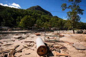Father walks through debris covering a field in the aftermath of Hurricane Helene, Wednesday, Oct. 2, 2024, in Chimney Rock Village, N.C.