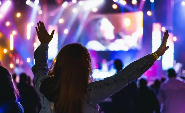 worship concert in a church woman raised hands. By Eduardo/stock.adobe.com