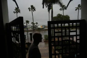 Christian Burke stands at the door of his home, where he, his mother, and his aunt plan to ride out Hurricane Milton on the third floor overlooking overlooking Tampa Bay, in Gulfport, Fla., Wednesday, Oct. 9, 2024. Burke, who said his engineer father built the concrete home to withstand a Category 5 hurricane, expects his raised ground floor to get up to 8 feet of water in Milton. A boat deposited by Hurricane Helene sits lodged in the bay front park outside his front door. (AP Photo/Rebecca Blackwell) Tropicana Field