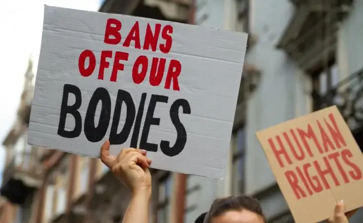 Protesters holding signs Bans Off Our Bodies and Human rights. People with placards supporting abortion rights at protest rally demonstration. By LongfinMedia/stock.adobe.com. abortion ban