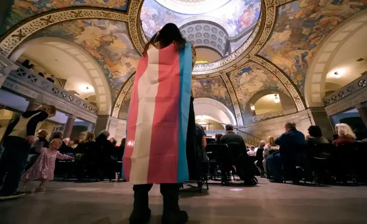 Glenda Starke wears a transgender flag as a counter protest during a rally in favor of a ban on gender-affirming health care legislation, March 20, 2023, at the Missouri Statehouse in Jefferson City, Mo. (AP Photo/Charlie Riedel, File) puberty blockers