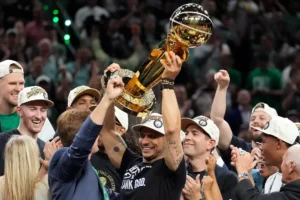 Boston Celtics head coach Joe Mazzulla, center, celebrates with the team as he holds up the Larry O'Brien Championship Trophy after they won the NBA basketball championship with a Game 5 victory over the Dallas Mavericks, Monday, June 17, 2024, in Boston. (AP Photo/Charles Krupa)