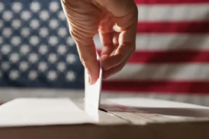 Hand reaching into the ballot box. By francescosgura/stock.adobe.com. Election day 2024