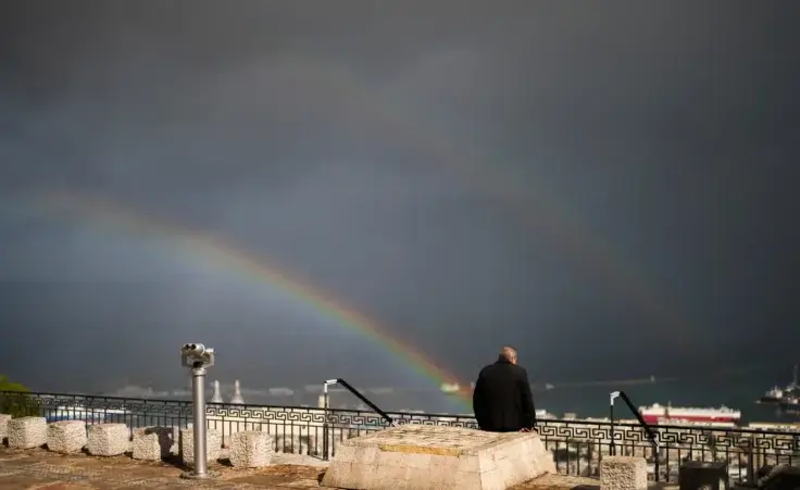 A rainbow stretches across the sky as a man sits in a promenade overlooking Haifa, Israel, Tuesday, Nov. 26, 2024. (AP Photo/Francisco Seco) Ceasefire Israel