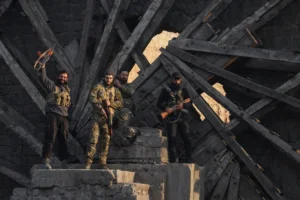 Insurgent fighters celebrate in the aftermath of the opposition's takeover of the city in downtown Hama, Syria, Friday, Dec. 6, 2024. (AP Photo/Omar Albam)