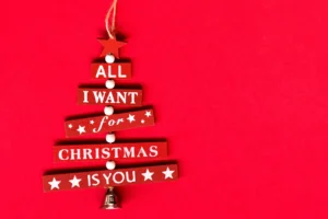 Christmas red tree decoration in red background with sentence, stars, and bell. By Diana/stock.adobe.com Mariah Carey